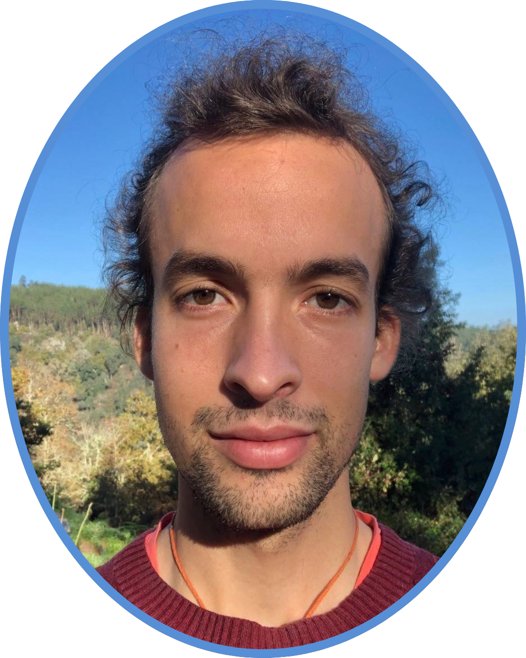 Noel Schraner blickt ruhig in die Kamera, im Hintergrund blauer Himmel und Waldlandschaft